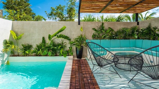 A pool area with a wooden pergola, a seating area with metal chairs, and lush greenery. - House with Private Pool, Roof Garden, and BBQ Grill (Playa del Carmen)