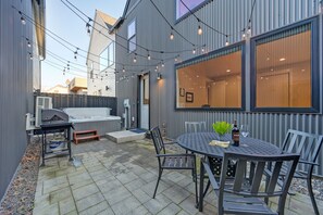 Un espace patio équipé d’un barbecue, de sièges d’extérieur et de guirlandes lumineuses.