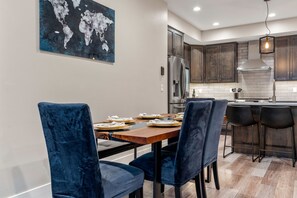 Une cuisine moderne avec des meubles de couleur bois foncé, un réfrigérateur en acier inoxydable et une œuvre d’art représentant une carte du monde accrochée au mur.