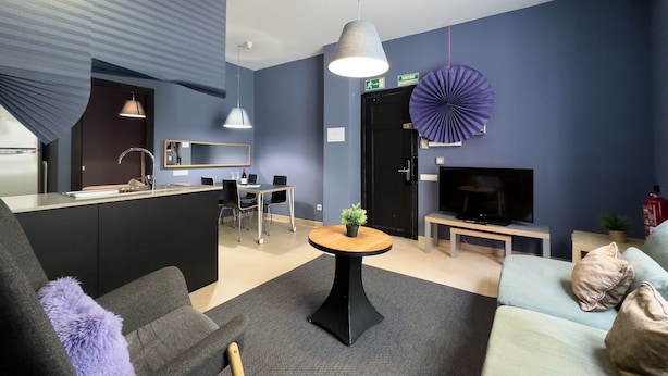 A modern living room with a sofa, a coffee table, a TV, and a dining area with chairs and a table. - Cosy studio close to city center in Sants (L'Hospitalet de Llobregat)