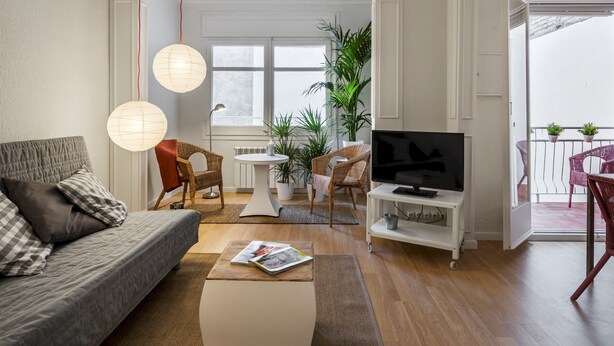 A modern living room with a sofa, coffee table, TV stand, and potted plants. - Comfortable 3-bedroom apartment with terrace, close to the center (L'Hospitalet de Llobregat)