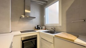 A compact kitchen with a built-in oven, a sink, and a window above the countertop. - Comfortable 3-bedroom apartment with terrace, close to the center (L'Hospitalet de Llobregat)