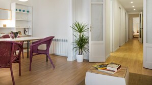 A modern living room with a dining area, a potted plant, and a wooden coffee table with books. - Comfortable 3-bedroom apartment with terrace, close to the center (L'Hospitalet de Llobregat)