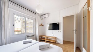 Ein modernes Hotelzimmer mit einem großen Bett, einem an der Wand montierten Fernseher und einer hölzernen Bank.