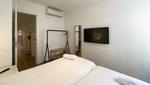 Ett hotellrum med en säng, en tv som är monterad på väggen, en trästege och en spegel.