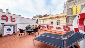 Terraza en la azotea con lavadora, una mesa con sillas y sillones.