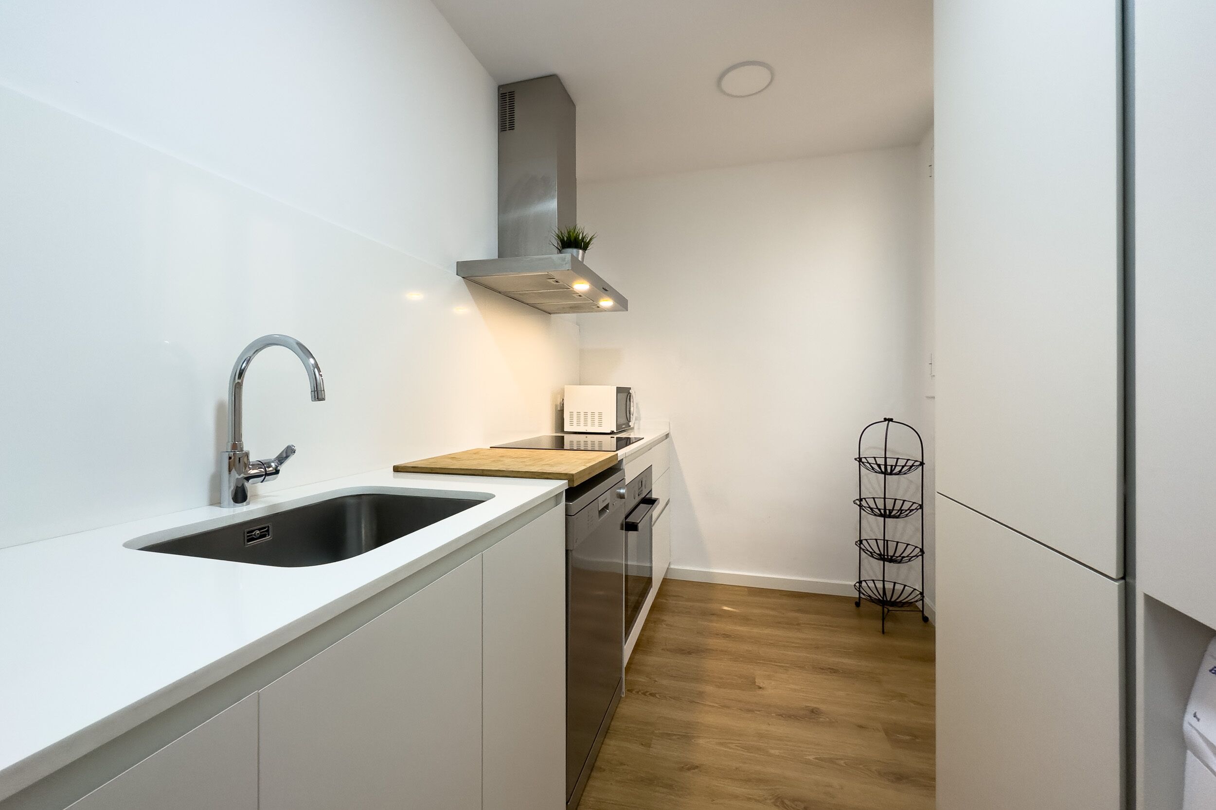 Een moderne keuken met een roestvrijstalen spoelbak, een magnetron en een ingebouwde oven.