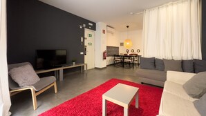 A modern living room with a TV, sofa, and red carpet.