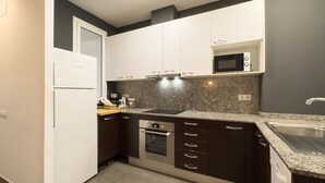 A modern kitchen with white cabinets, a granite countertop, a built-in microwave, a stainless steel sink, and an oven.