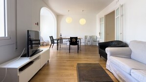 Ein modernes Wohnzimmer mit Flachbildfernseher, einer Couch und einem Essbereich mit Stühlen und einem Tisch.