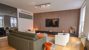 En moderne stue med en hjørnesofa, en hvid lænestol og et lille, orange sofabord.