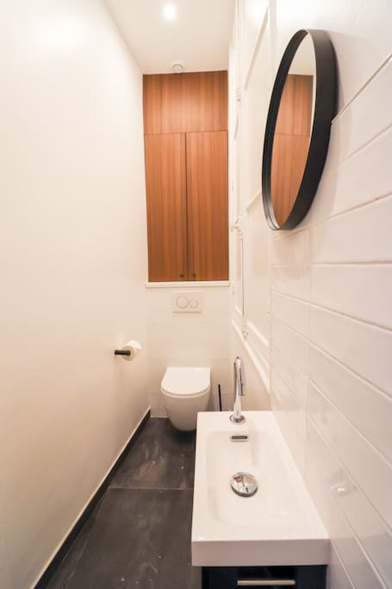 A small, modern bathroom with a white sink, a mirror, and a toilet.