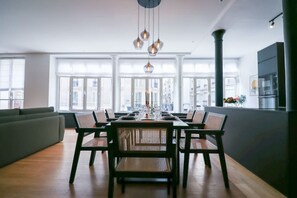 Zona de dinar moderna amb taula gran, cadires i lluminàries penjants.