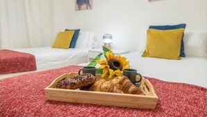 A breakfast tray with croissants and a muffin on a red textured rug, a sunflower, and two mugs on a bed with white bedding and yellow pillows. - Urban Exclusivity At Puerto Banús (Marbella)