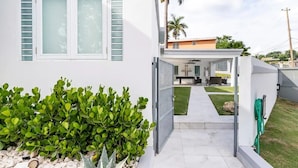 A modern house with a covered patio, a small garden, and a view of the backyard. - Luxury Casa CALIAD (San Juan)