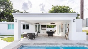 A modern outdoor pool area with a covered patio, seating, and a pool table. - Luxury Casa CALIAD (San Juan)