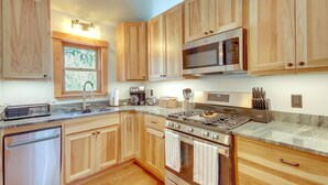A modern kitchen with wooden cabinets, stainless steel appliances, and a marble countertop. - Secluded Livingston Retreat w/ Deck + Fire Pit! (Livingston)