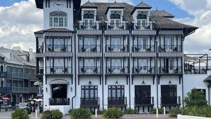Un immeuble à plusieurs étages, doté d’une tour horlogée, de nombreux balcons et d’une pelouse bien entretenue.