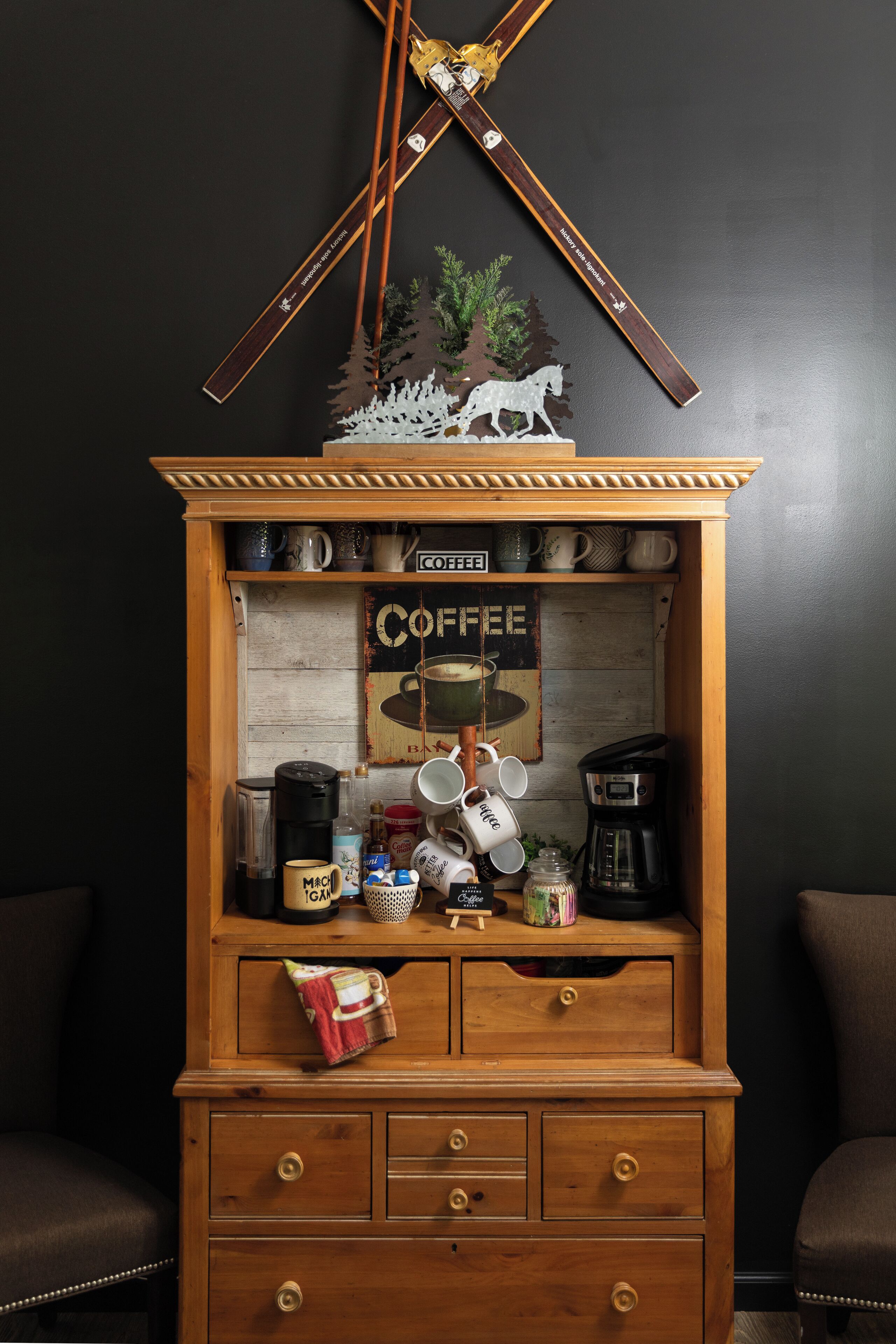 A wooden coffee station with a coffee machine, mugs, and a sign that says "COFFEE."