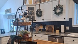 Une cuisine moderne avec des armoires blanches, un plan de travail en bois et un panneau d’accueil.