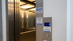 Interior de ascensor con información de contacto de emergencia e instrucciones de uso.