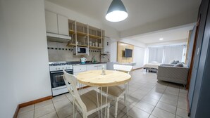 Una cocina moderna con gabinetes blancos, una mesa redonda de madera y un microondas integrado.