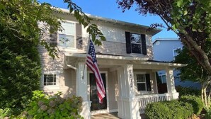 Ein zweistöckiges Haus mit Veranda und einer amerikanischen Flagge.