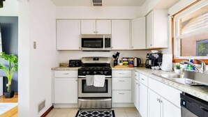 A modern kitchen with white cabinets, a stainless steel stove, a microwave, and a sink. - Curated for Cozy Stays -2 Parking Spaces, Sleeps 4 (Westmont)