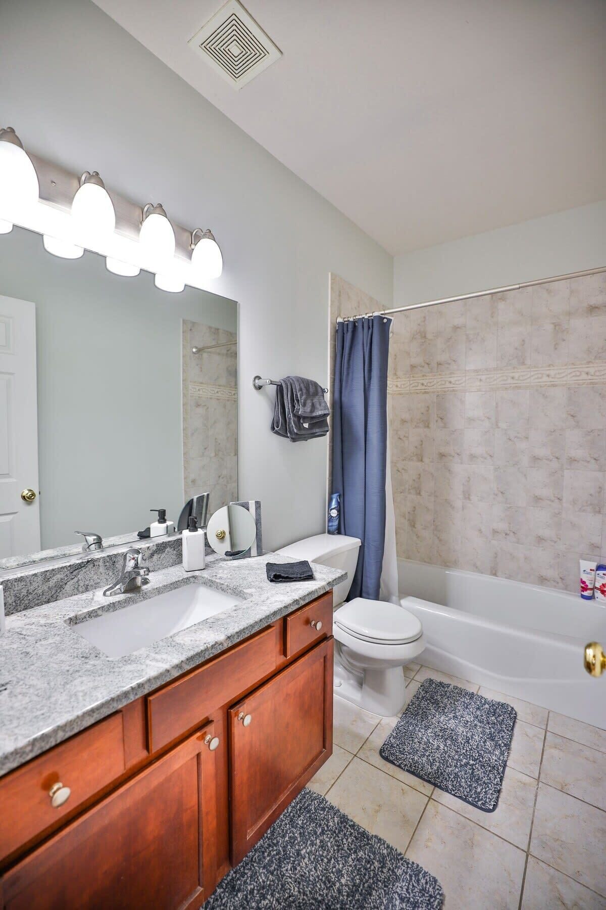A bathroom with a marble sink, vanity, and a bathtub.