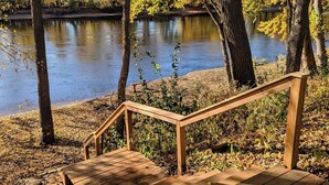 Eine Holzterrasse mit Metallgeländer, das zu einem Flussufer führt.