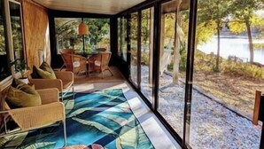 Ein Zimmer mit großem Fenster mit Seeblick, Holzboden und einem gemusterten Teppich.
