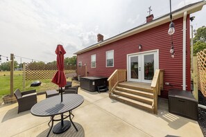 Una casa roja con un patio, mobiliario exterior y un jacuzzi.