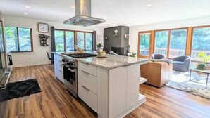 Una cocina moderna con una isla central, horno integrado y un amplio ventanal con vistas a una terraza.