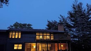 Una casa de dos pisos con un balcón y ventanas amplias.