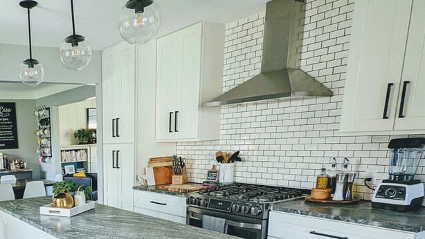 Una cocina moderna con armarios blancos, una isla central, una estufa y una licuadora.