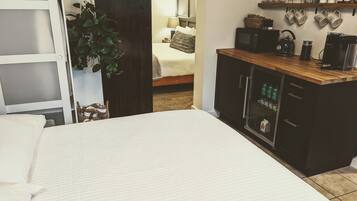 Una camera da letto con un letto, un armadio in legno con frigorifero e una pianta.