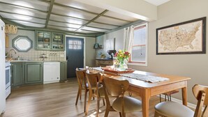 A kitchen with wooden cabinets, a dining table with chairs, and a map on the wall. - Cozy Lakeside Cottage for Families and Fun Seekers. Game room - Large Soaker Tub (Council Bluffs)