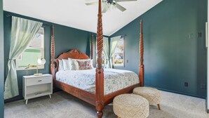A four-poster bed with a wooden frame, a nightstand with a lamp, and two ottomans. - Cozy Lakeside Cottage for Families and Fun Seekers. Game room - Large Soaker Tub (Council Bluffs)