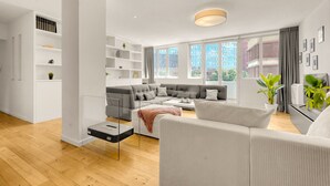 A modern living room with a sectional sofa, a coffee table, and a glass shelf unit. - Le Bonrepos - T3 sur les Ramblas de Toulouse (Toulouse)