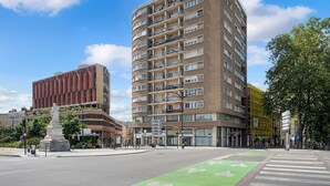 A multi-story building with balconies, a statue, and a green bike lane. - Le Bonrepos - T3 sur les Ramblas de Toulouse (Toulouse)