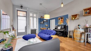 A modern living room with a blue sofa, a piano, and a coffee table. - Bleu du Maine - Elegant T3 avec terrasse (Toulouse)