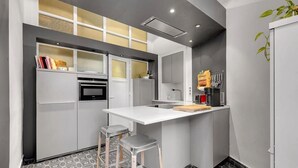 A compact kitchen with a white countertop, two stools, a microwave, and a coffee machine. - Bleu du Maine - Elegant T3 avec terrasse (Toulouse)