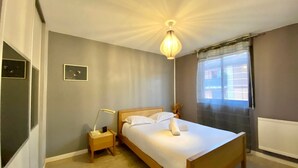 Una camera da letto con un letto, un comodino, una lampada e una finestra con tende.