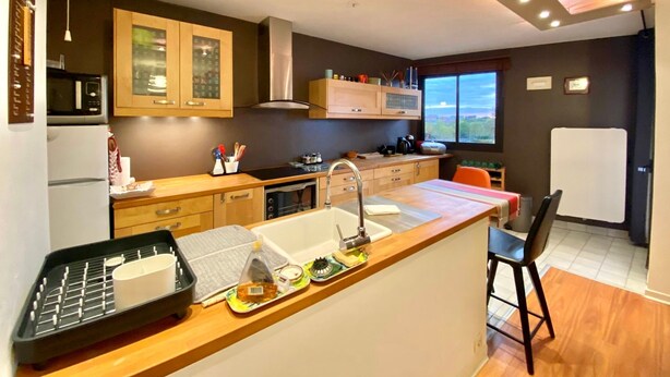 Una cucina moderna con mobili in legno, un forno a microonde, un lavello e un'area pranzo con una sedia.