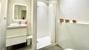 Un baño moderno con ducha de vidrio, tocador con espejo y inodoro.