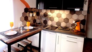 Une cuisine de taille réduite avec une table en bois, des placards blancs et un dosseret de crédence en carreaux hexagonaux.
