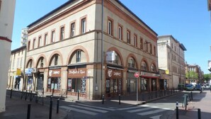 Un immeuble d’angle doté de plusieurs devantures de magasins, dont un restaurant et une boutique avec une enseigne indiquant « BIO ».