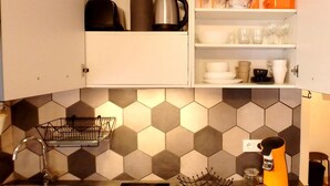 Une cuisine dotée d’un plan de travail avec des carreaux hexagonaux, d’un évier, d’une bouilloire, d’une machine à café et de divers ustensiles de cuisine.