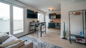 A modern apartment with a kitchen, dining area, and a large window. - Carré d’As - Appartement de standing (Le Bourget)