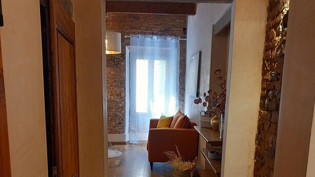 A hallway leading to a living area with a sofa, a rug, and a brick wall. - Clery house, a stone's throw from Florence, Tuscan style (Montelupo Fiorentino)